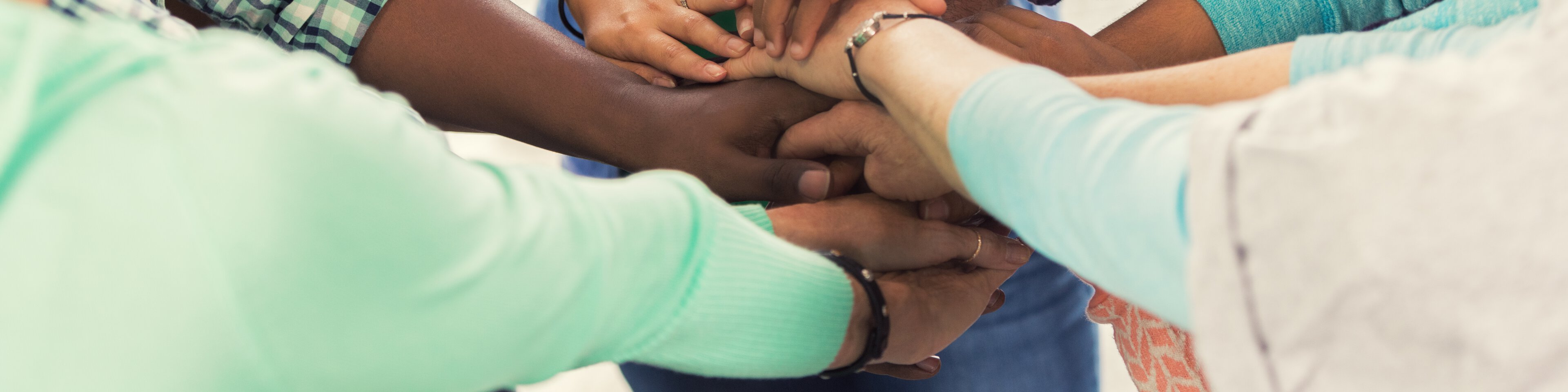 Junge Menschen legen Ihre Hände beim Freiwilligendienst aufeinander | © Steve Debenport/Getty Images